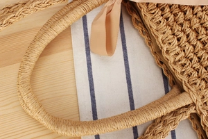 Macro view of bohemian paper rope woven beach bag with silk bow and zipper detail