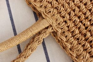 Detail of bohemian paper straw bag featuring intricate weave texture and reinforced handle