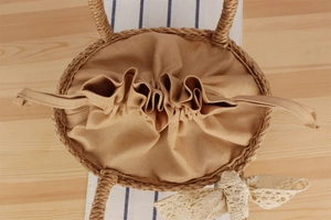 Detail of handmade woven paper rope beach bag with drawstring closure and lace bow