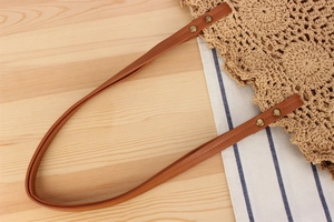 Detail of woven tote bag with brown leather handles and brass rivets for beach vacations