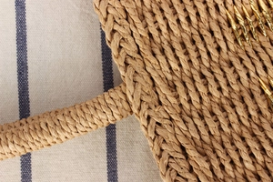 Macro detail of hand-woven straw beach bag featuring gold metallic thread accents