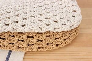 Close-up of hand-woven crochet tote bags in beige and brown showing detailed hollow texture