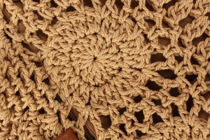 Detail shot of radial woven pattern and straw texture on a large khaki tote bag