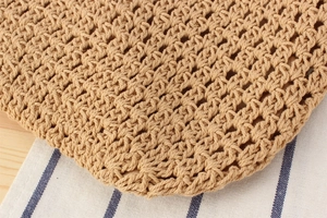 Close-up of hand-woven straw bag texture featuring detailed crochet patterns and beige lining