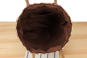 Interior view showing brown fabric lining with zipper pocket of woven straw bag