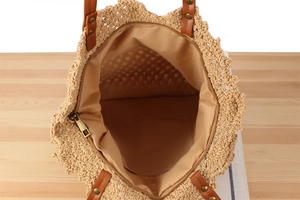 Detail view of large woven bag interior with fabric lining and brown leather handle