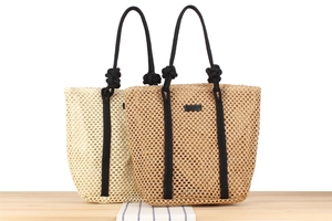 Detail of hollow woven beach tote bags in beige and tan with knotted black rope handles