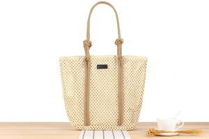 Detailed close-up of beige woven tote bag featuring crochet patterns and brown rope handles