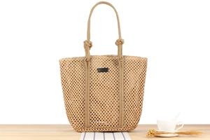 Minimalist woven tote bag in khaki with knot handles on a light wooden table surface