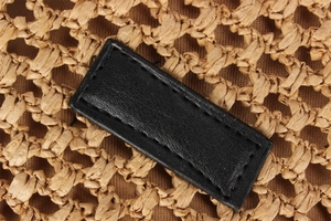 Close-up of woven straw texture with a black leather patch and neat stitching detail