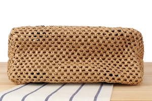 Close-up of the intricate natural fiber woven texture and grid pattern on the straw bag