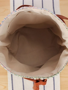 Multicolor woven tote bag with brown leather handles and spacious interior lining