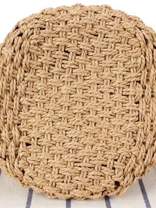 Handcrafted round straw woven bag with intricate texture on a blue striped fabric background