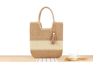 Detalle de un bolso tote de paja tricolor con un colgante de borla y cuentas de madera