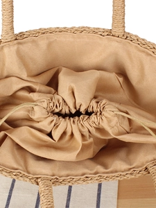 Top view of a woven straw beach bag featuring a khaki drawstring lining and secure interior