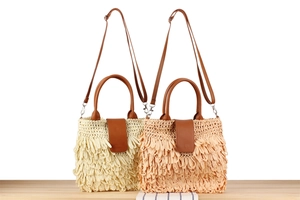 Detail of woven straw shoulder bags with fringe tassels in beige and light brown