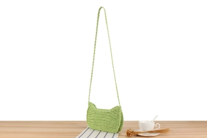 Dettaglio della borsa a tracolla intrecciata in corda verde chiaro in set estivo