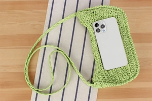 Dettaglio della borsa per cellulare in paglia intrecciata verde chiaro con smartphone