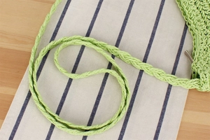 Dettaglio della borsa in paglia di carta verde chiaro con manico intrecciato e fibra