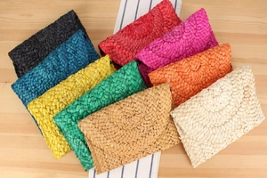 Flat lay of colorful handmade corn husk straw clutch bags on a rustic wooden table