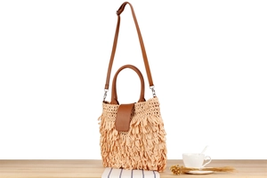 Close-up of beige woven shoulder bag with long fringe tassels and leather handle