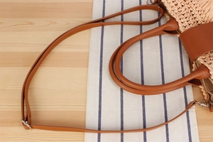 Close-up of woven texture with brown leather strap and silver metal buckle detail