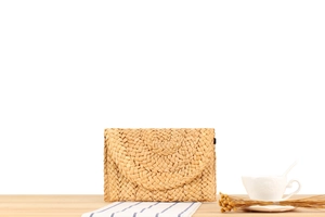Detail of handmade corn husk straw envelope clutch bag with woven texture on wood