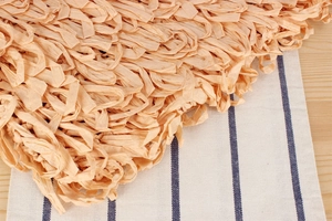 Close-up of woven paper rope fringe detail on an apricot bohemian beach shoulder bag