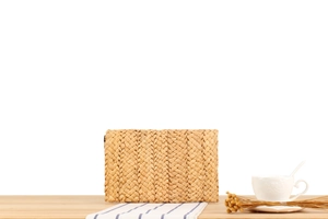 Detailed view of handmade woven corn husk clutch bag on a rustic wooden table setup