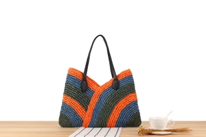 Detail of colorful woven tote bag with orange and blue stripes on a wooden desk