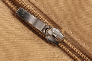 Macro view of silver metal zipper and durable khaki woven texture on shoulder bag
