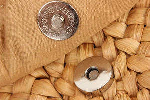 Detail of the magnetic buckle closure on a handmade corn husk woven handbag with soft lining