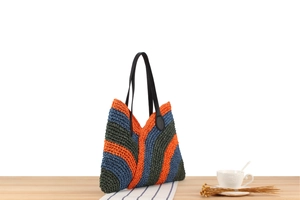 Detail of colorful woven tote bag with leather handles on a minimalist wooden table