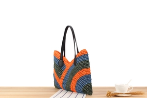 Close-up of handmade woven tote bag featuring orange and blue wave pattern and leather straps
