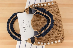 Detail of straw woven handbag with blue ruffles and white pearl accents on light wood