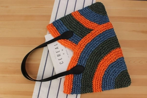 Detail of handmade woven tote bag with orange and blue stripes and leather handles