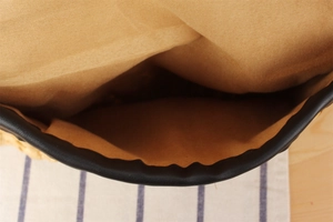 Detail of the woven corn husk bag showing camel fabric lining and black faux leather trim