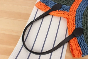Close-up of colorful woven beach bag stripes with black leather shoulder straps