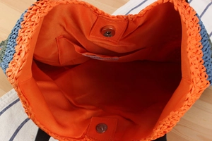 Detail view of colorful woven tote interior with orange lining and magnetic snap closure