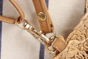 Detalle macro del cierre de metal dorado y correa de cuero en el bolso de paja tejido