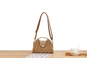 Detail of paper straw woven crossbody bag with bead accents and leather strap