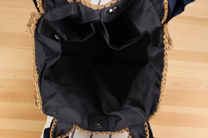Interior view of straw tote bag with navy fabric lining, multi-pockets, and magnetic clasp