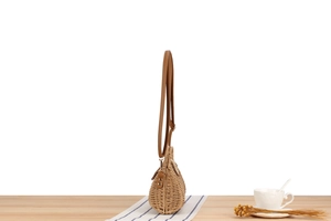 Side view of hand-woven paper rope crossbody bag with premium leather strap on a table