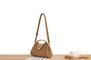 Detail of woven straw handbag with beaded embroidery flap and brown leather strap