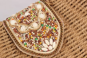 Macro view of woven paper rope bag featuring colorful beads and metal chain edge