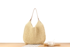 Gros plan du sac fourre-tout en corde de papier beige avec lanières brunes sur bois