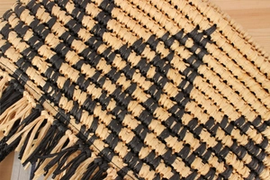 Macro shot of ethnic woven straw bag with black tassel trim and checkered pattern