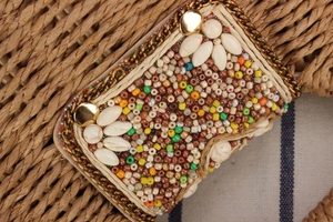 Macro shot of colorful beads and ivory floral accents on handwoven paper rope bag