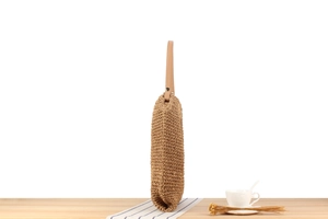 Détail de la texture en paille tressée et de la bandoulière en similicuir du sac à main