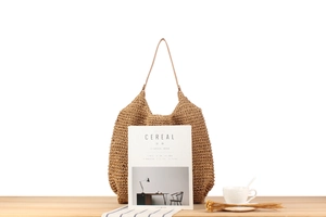 Détail d'un sac en paille tissé à la main sur une table en bois avec un éclairage doux